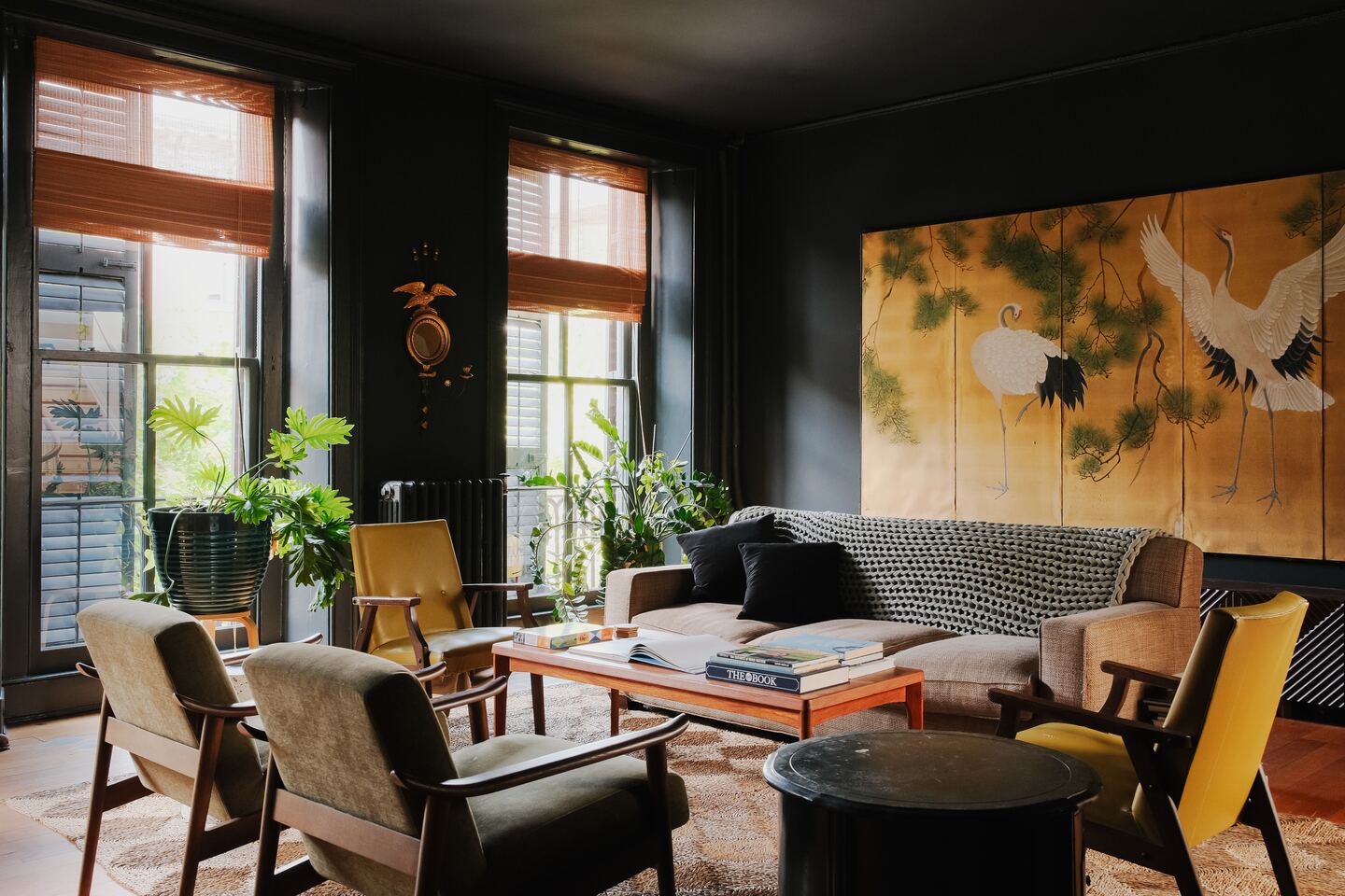 The library: black walls, low sun through the blinds and a gold screen painted with cranes
